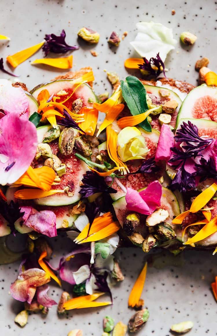 Gourmet dish topped with figs, edible flowers, and pistachios