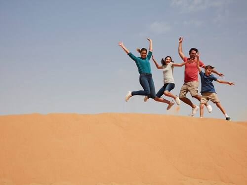 Family jumping on desert in Dubai